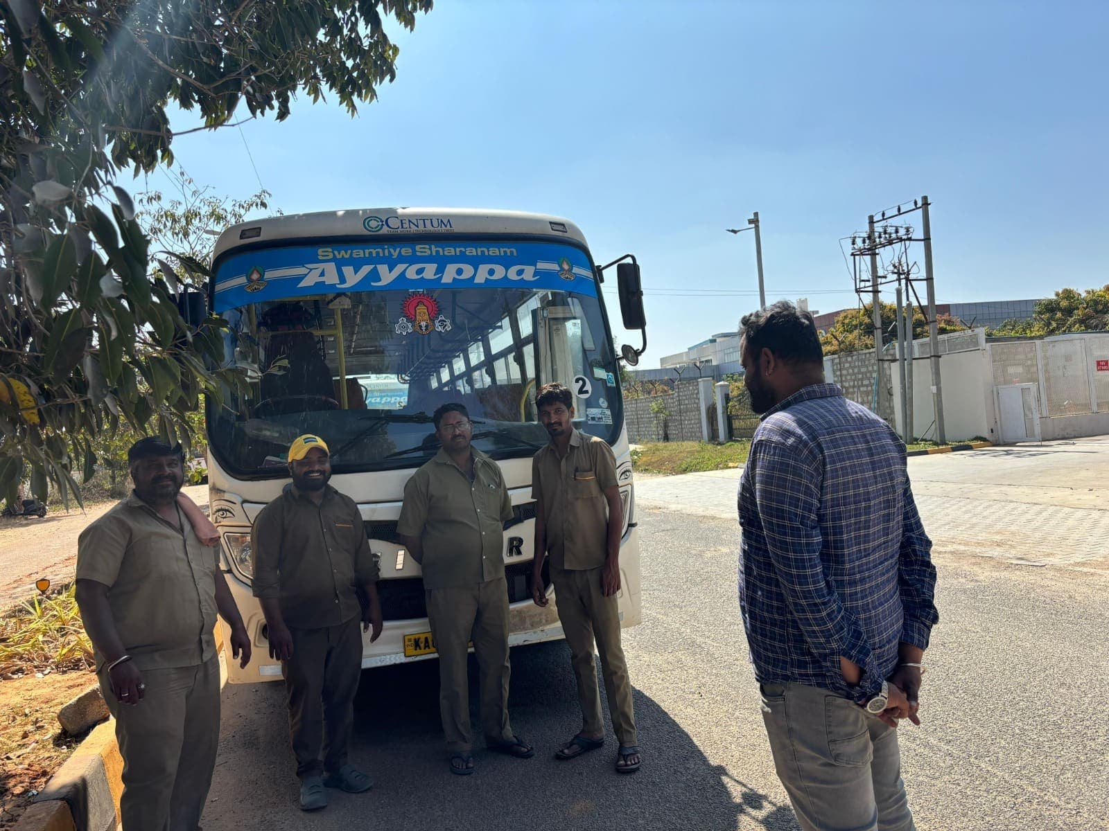 Supervisor briefing uniformed drivers in front of a Sree Ayyappa Tourist corporate bus