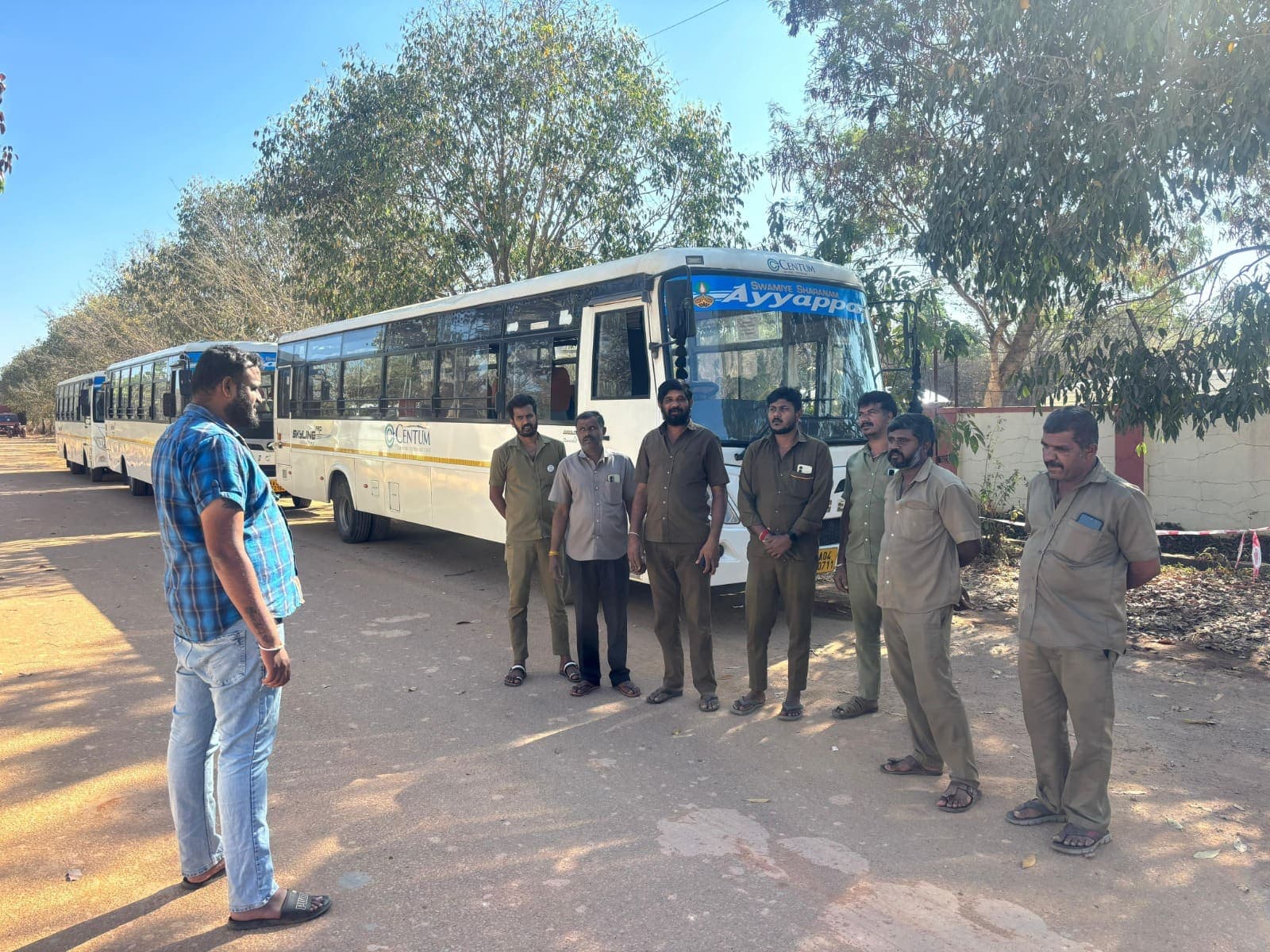 Supervisor addressing a group of uniformed drivers beside the corporate bus fleet