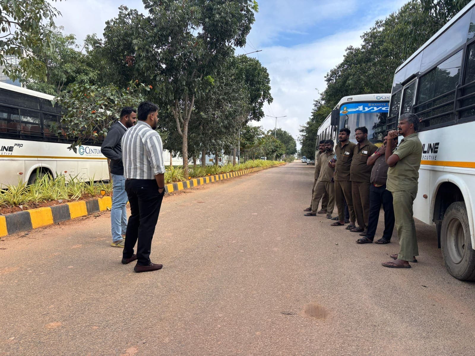 Operations managers reviewing the day's routes with drivers between parked corporate buses